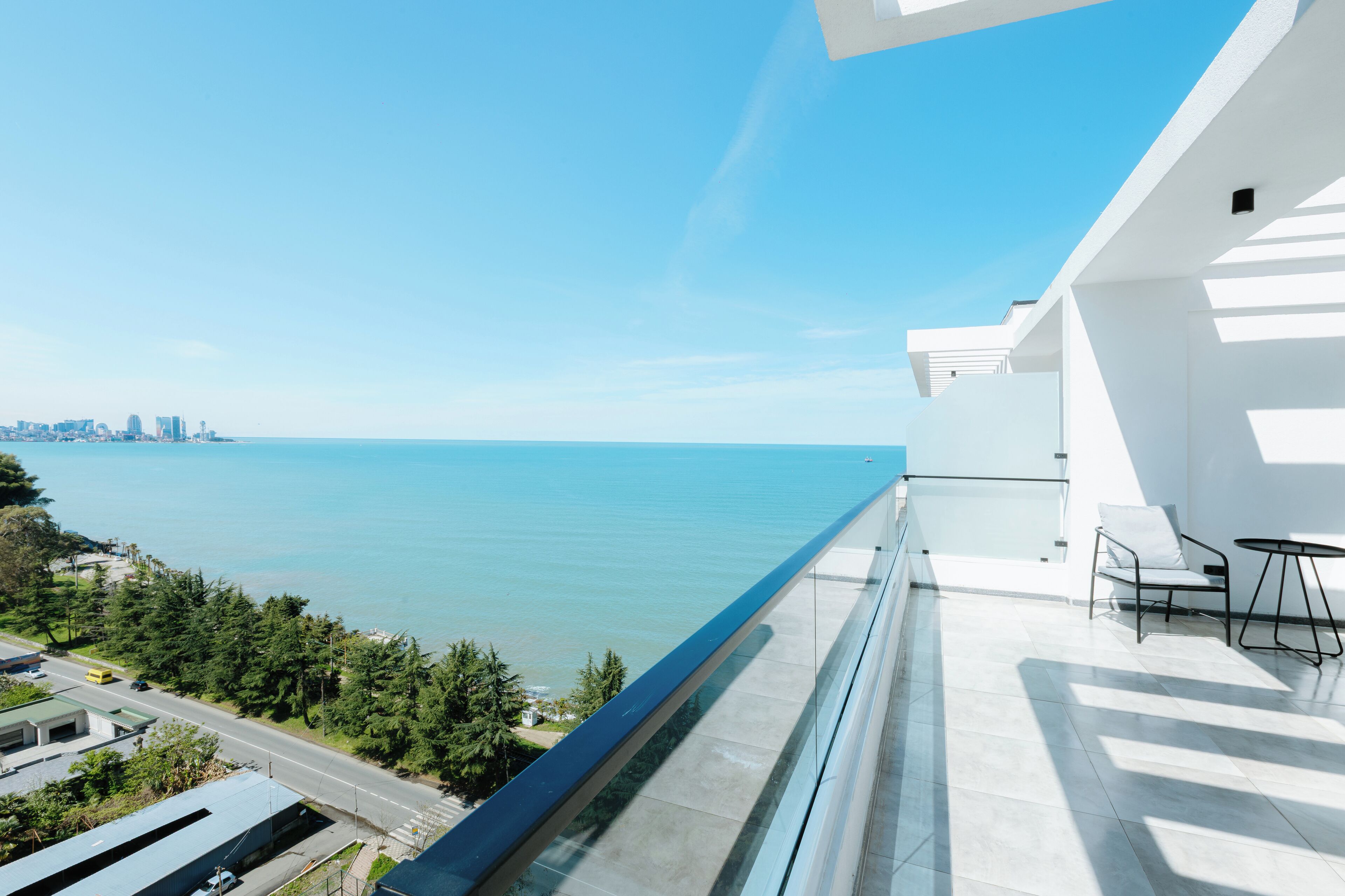 A balcony with a clear view of the sea and city skyline.
