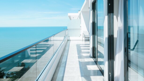 Een modern gebouw met een glazen balkon met uitzicht op zee.