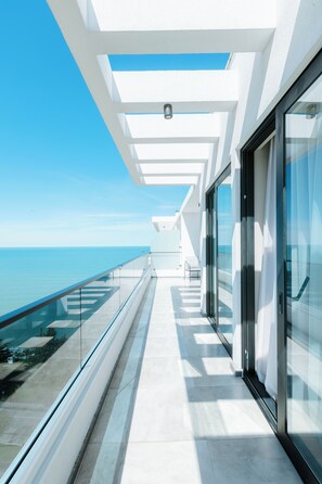 Un edificio moderno con un balcone in vetro affacciato sul mare.