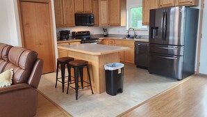 A modern kitchen with wooden cabinets, a stainless steel refrigerator, a built-in oven, and a coffee maker.