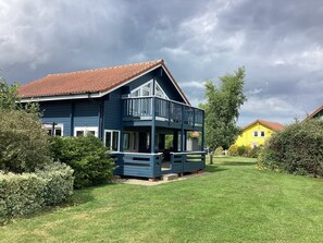 A two-story house with a balcony, surrounded by well-maintained lawns and trees. - Honeypot Lodge
Scandinavian Style, on-site golf course. (Fritton)