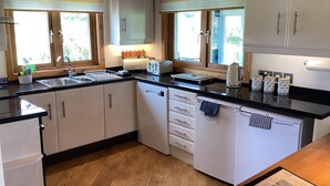 A modern kitchen with white cabinets, a black countertop, and wooden flooring.