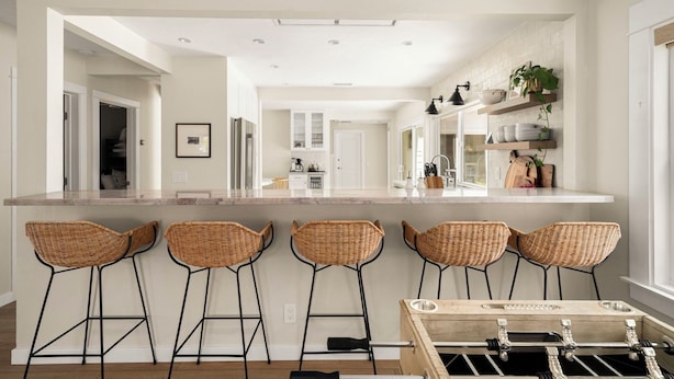A kitchen with a central island, four bar stools, and a wooden coffee table. - Belmont Beach Escape: Private Pool and Hot Tub + Steps to the Sand (Long Beach)
