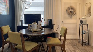 Ein Essbereich mit einem runden Tisch, zwei Stühlen, einer Kaffeemaschine und einem Fernseher.