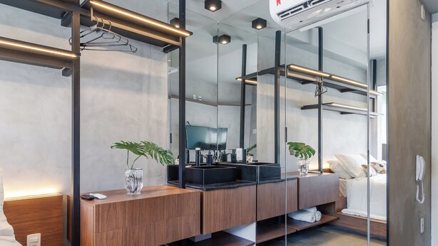 A modern bathroom with a wooden vanity, dual sinks, a large mirror, and a glass shower enclosure. - Akile Be Urban (Sao Paulo)