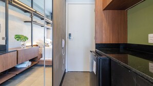 A modern hotel room with a wooden vanity, a glass shower enclosure, a white door, and a black countertop. - Akile Be Urban (Sao Paulo)
