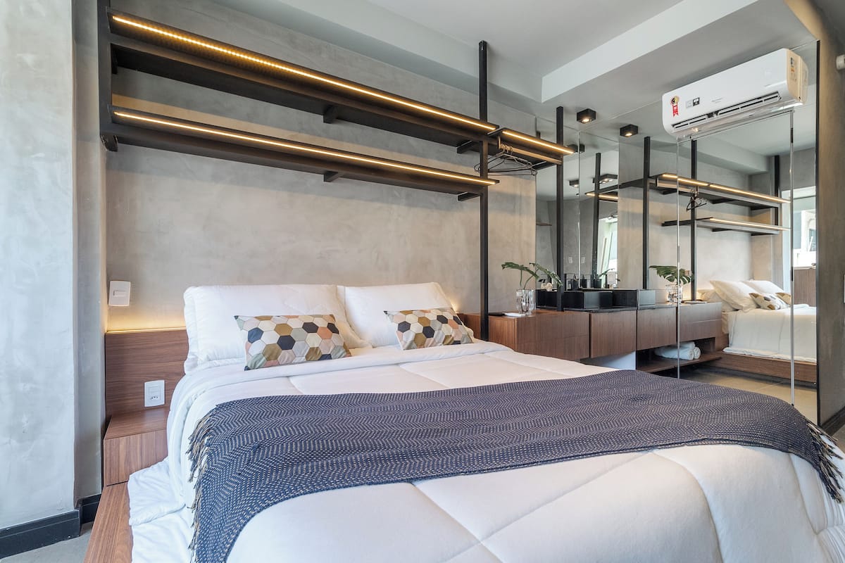 Moderni hotellihuone, jossa on suuri sänky, yöpöydät, lipasto ja iso peili.