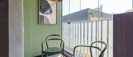 A room with a large window, two chairs, a hanging light fixture, and a framed artwork on the wall.