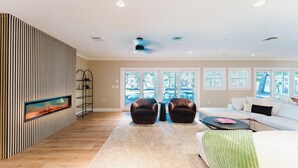 A modern living room with a fireplace, two leather armchairs, a white sofa, and a green throw.