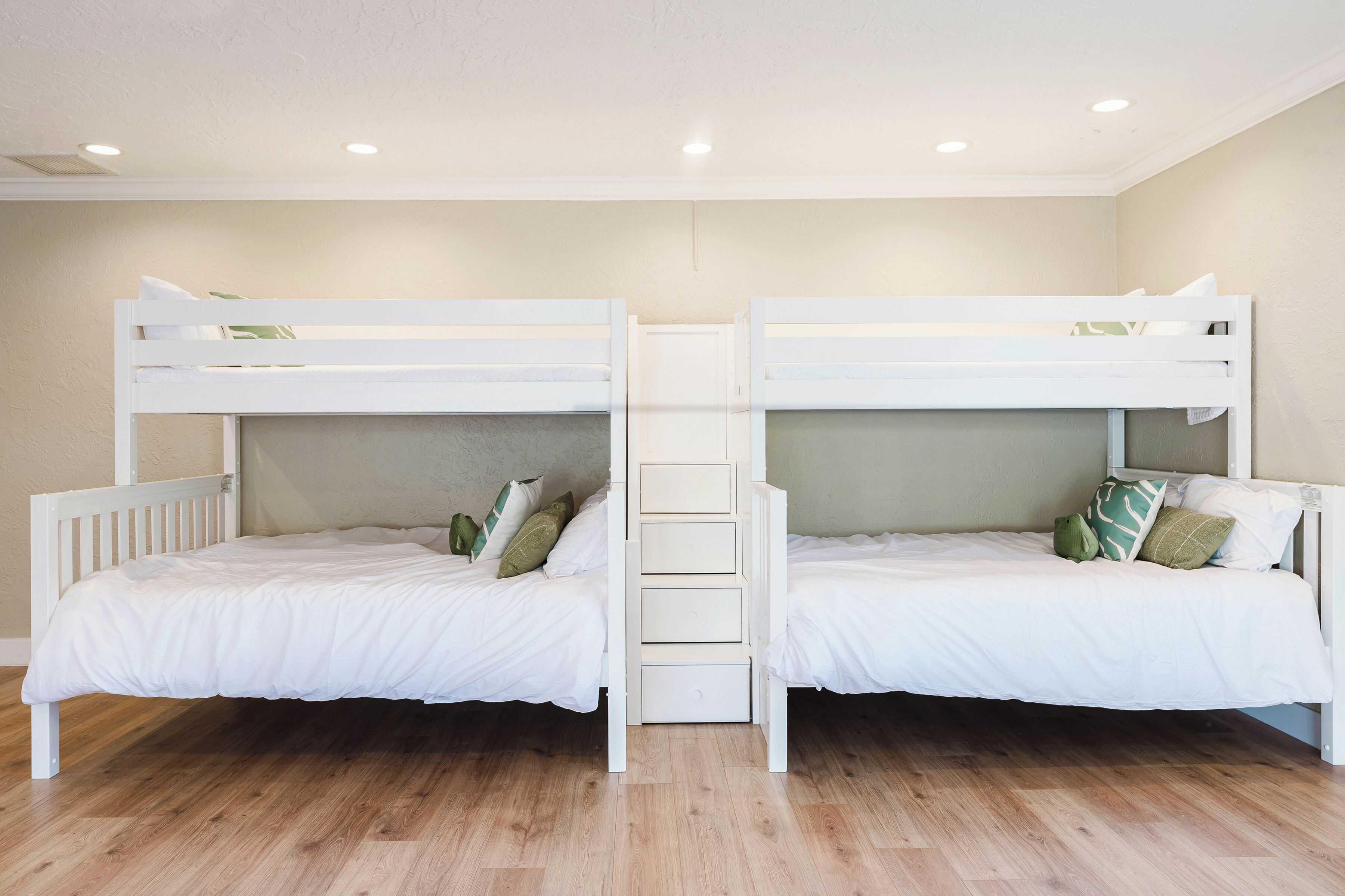 Una habitación con dos literas, suelo de madera y una decoración en tonos blancos.