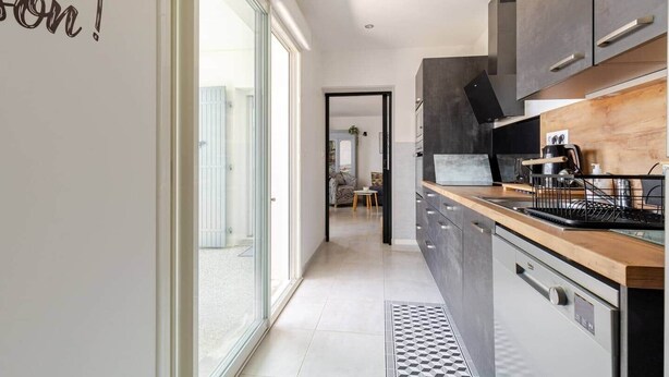 A modern kitchen with dark cabinets, a wooden countertop, and a black range hood. - "Chez Céline et Frédéric" : house n°1 / T3 60m2 (Rochefort)