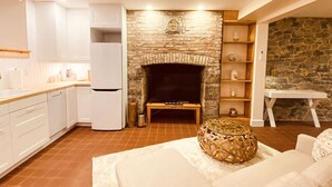 A modern kitchen with white cabinets, a built-in oven, and a stone fireplace.
