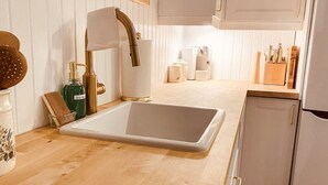 A kitchen with a white sink, wooden countertop, and white cabinets.