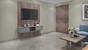 Een moderne woonkamer met een flatscreen televisie bevestigd aan een houten wandpaneel, een grijze console tafel met decoratieve objecten, een houten deur en een blauwe bank.