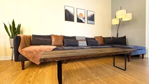 A modern living room with a sectional sofa, a coffee table, and a floor lamp. - The Neighbourhood: Expansive loft | free parking (Kingston)