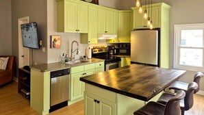 A kitchen with green cabinets, a wooden island, a dishwasher, a stove, and a refrigerator. - The Neighbourhood: Expansive loft | free parking (Kingston)