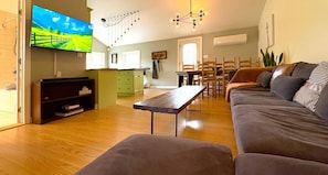A living room with a sofa, a coffee table, a TV, and a dining area with chairs and a table.