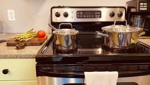 A kitchen with a stove, pots, a cutting board with vegetables, and a coffee maker. - The Neighbourhood: Expansive loft | free parking (Kingston)