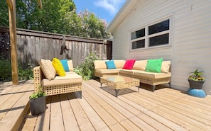 An outdoor patio with wicker furniture and potted plants.