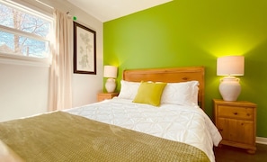 A bed with white bedding, a green wall, and two bedside lamps.