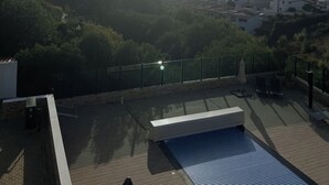 Un espace piscine aménagé sur le toit, offrant une vue sur la mer et les bâtiments en arrière-plan.