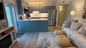 A modern kitchen with a central island, a dining area with a sofa, and a ceiling fan.
