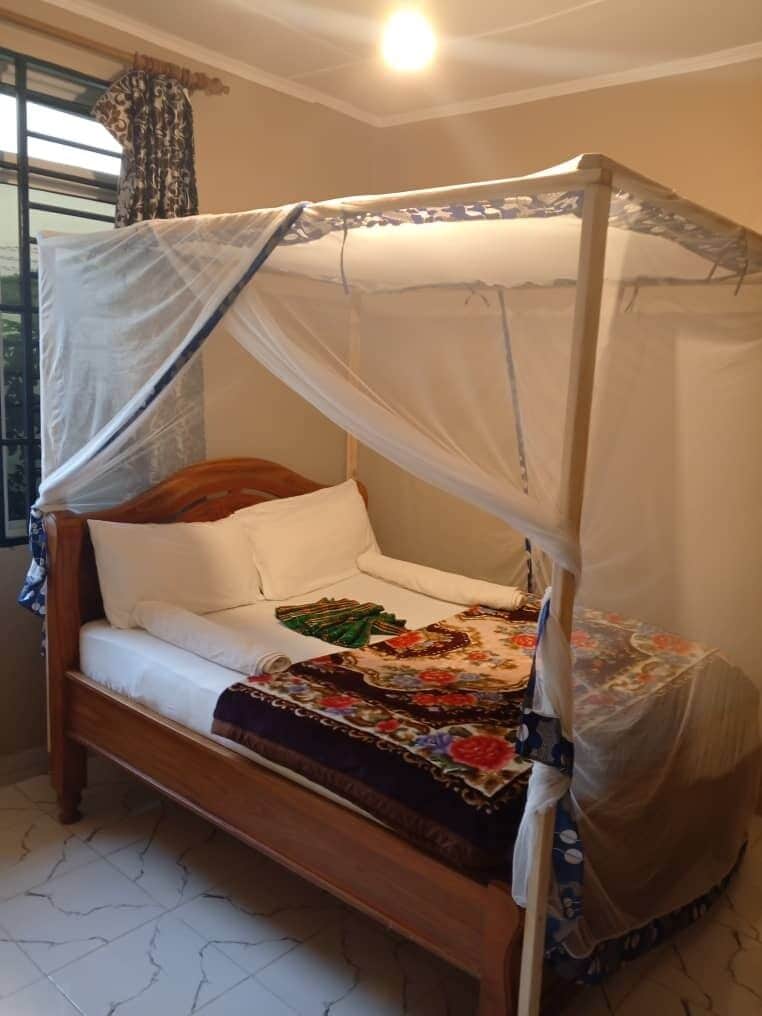 Una cama individual con dosel, cabecera de madera y colcha estampada con flores.