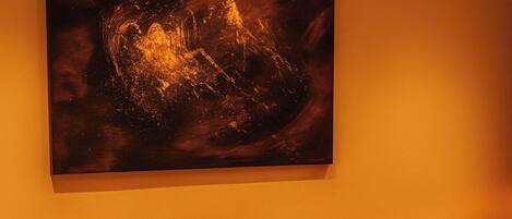 Un coin repas avec une table ronde, quatre chaises et un grand tableau abstrait accroché au mur.