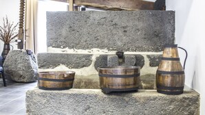 Un muro de piedra con tres barriles de madera y una cuenca de piedra.