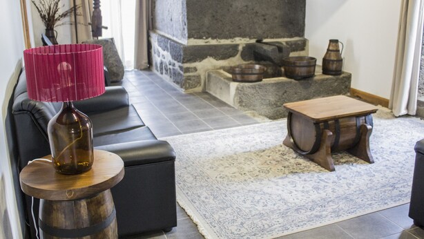Una sala de estar moderna con chimenea de piedra, un sofá de cuero negro, una mesa de centro de madera y una lámpara decorativa.