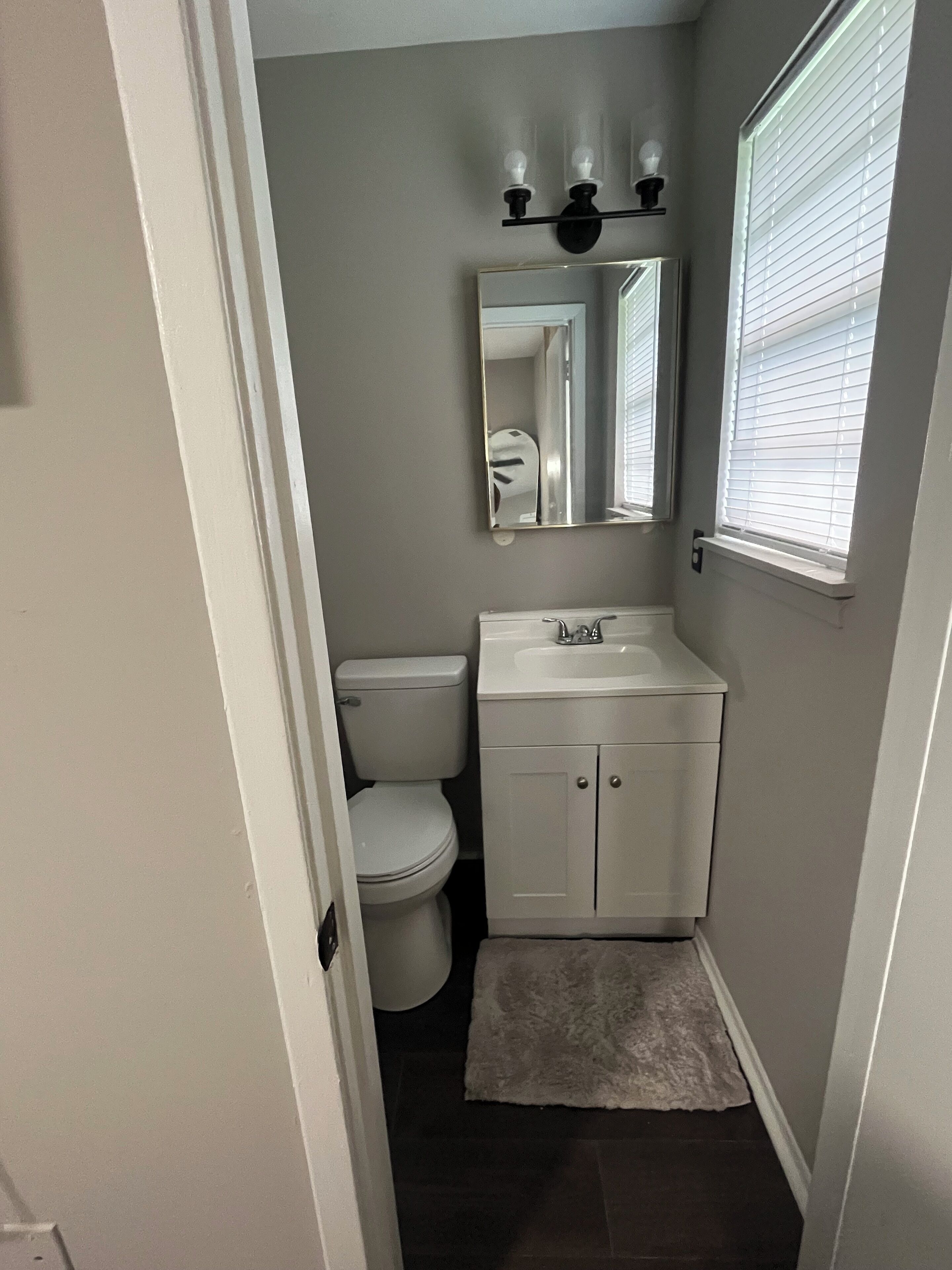 A compact bathroom with a toilet, sink, and mirror.