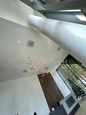 A modern interior with a high ceiling, geometric light fixtures, and a reception desk. - Easy Stay at the Lennox (Accra)