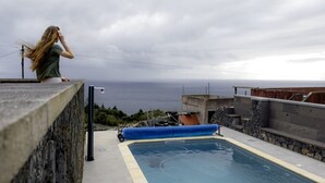 Une piscine avec vue sur l’océan, une bordure en béton et une piscine gonflable bleue.