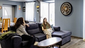 Un salon moderne avec un canapé gris foncé, une table basse en bois et une horloge décorative accrochée au mur.