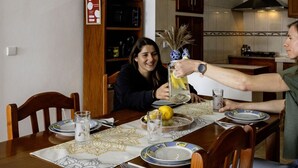 A wooden dining table set for two with plates, glasses, and a lemon.