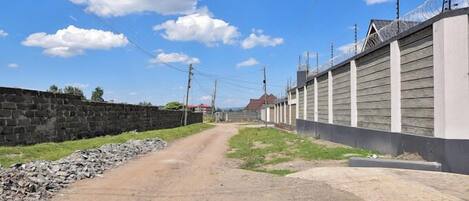 A dirt road flanked by a stone wall and a wooden fence with barbed wire.