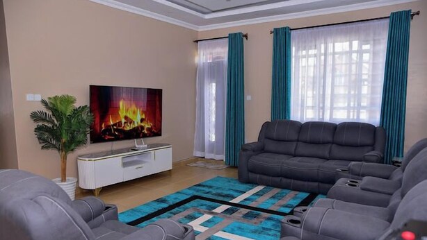 A living room with a sofa, a TV, a coffee table, and a plant. - Lux Suites comfy Homestays Nakuru (Nakuru)