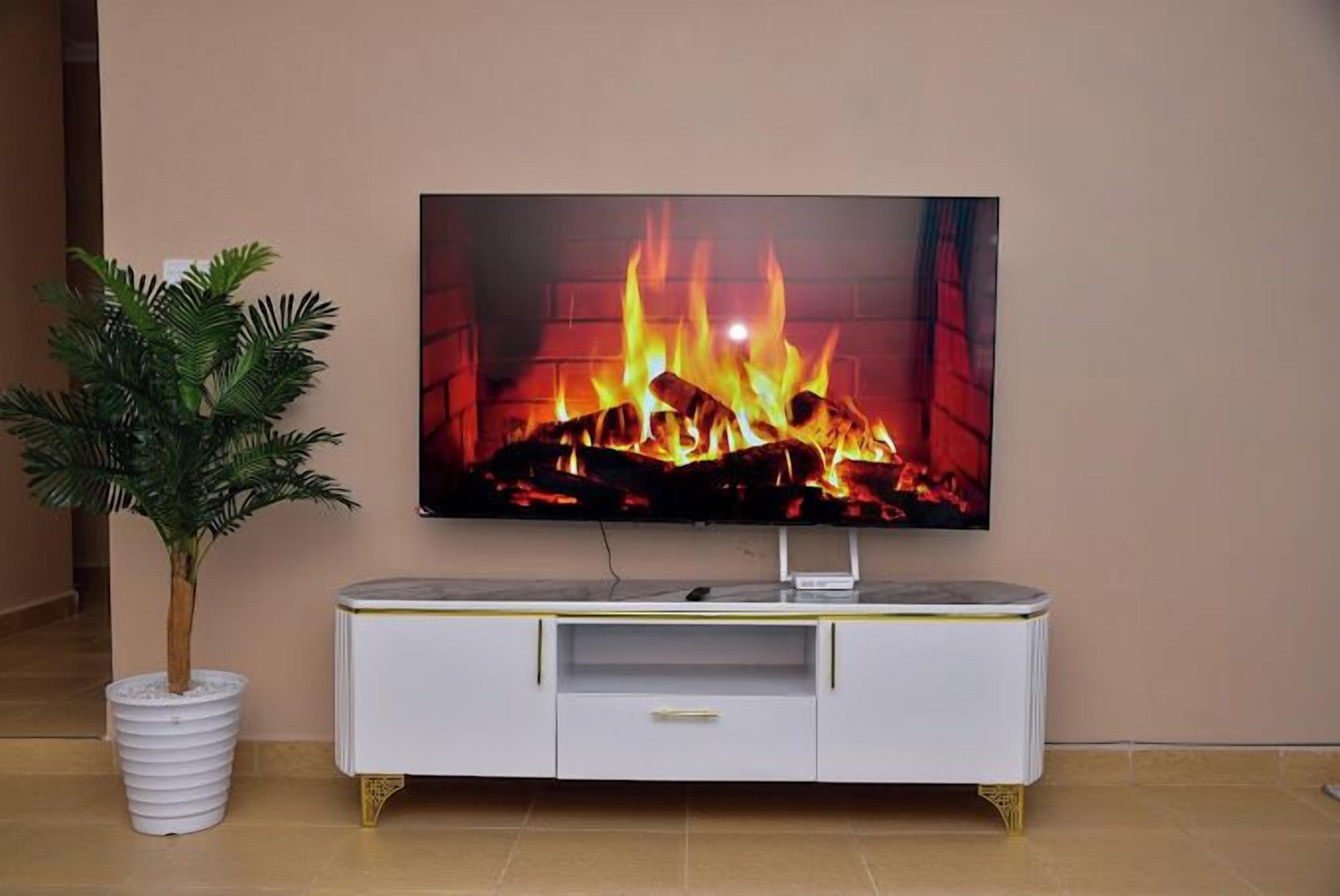 Een flatscreen televisie bevestigd aan een witte televisiemeubel met gouden poten, geplaatst tegen een muur.