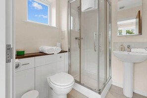 A modern bathroom with a glass-enclosed shower, a toilet, and a sink.