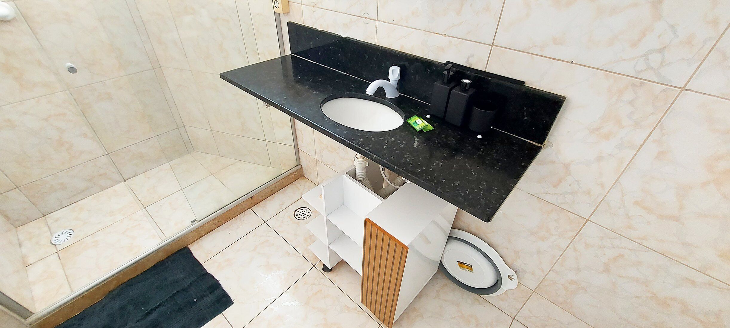 A bathroom with a black countertop sink, a white cabinet, and a shower area.
