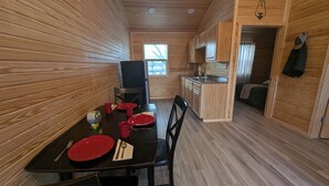 A wooden interior with a dining table set for four, a kitchen area, and a visible window. - Wichita's Spring Lake RV Resort (Halstead)