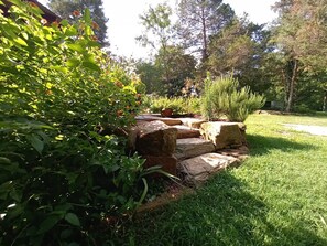 A garden with a stone staircase surrounded by lush greenery and flowering plants. - Charming cabin get away w/ walk-in shower, kitchenette, AC/heat, WiFi (Henderson)