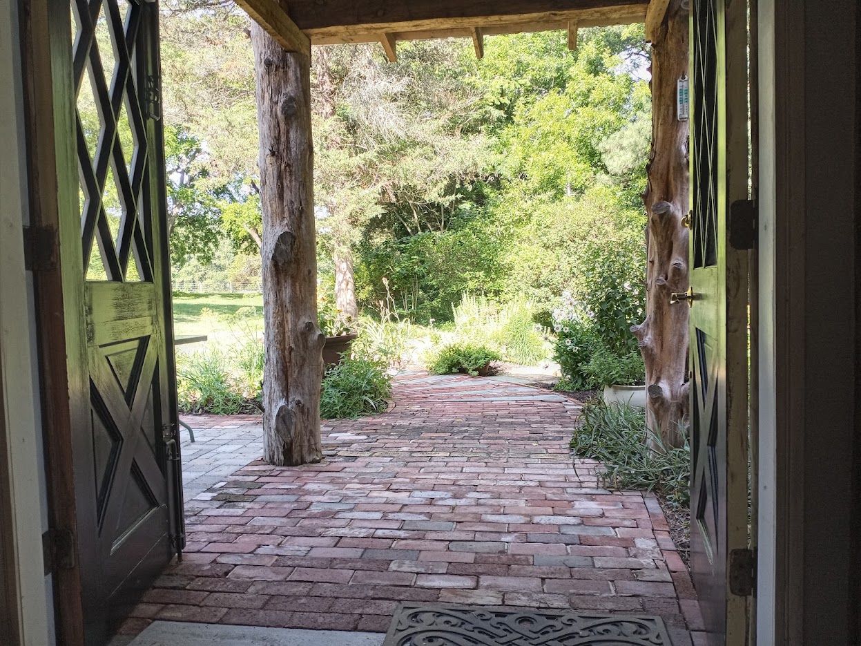 A brick pathway leading to a wooden structure with a metal gate.