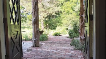 Un sendero de ladrillos que conduce a una estructura de madera con una reja de metal.