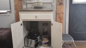 A compact kitchenette with a built-in blender, a small countertop, and a window with a curtain. - Charming cabin get away w/ walk-in shower, kitchenette,  AC/heat, WiFi (Henderson)