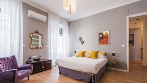 Un dormitorio moderno con una cama grande, un sillón clásico y un escritorio con una máquina de escribir.