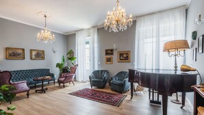 Un salón amplio con un piano de cola, un sofá azul y dos sillones.