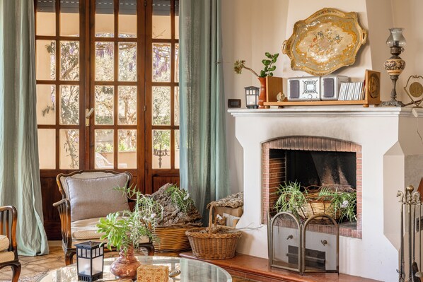Una sala acogedora con chimenea, cestas de mimbre y un sillón cómodo.