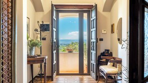 An open door leading to a balcony with a view of the sea, a piano, and a chair. - Galatea e Giardino delle Esperidi apartments with pool by Wonderful Italy (Syracuse)