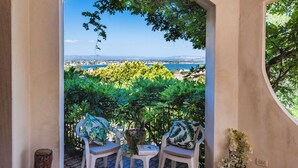 An outdoor seating area with two chairs and a table, overlooking a scenic view of a coastal landscape and a city in the distance. - Galatea e Giardino delle Esperidi apartments with pool by Wonderful Italy (Syracuse)